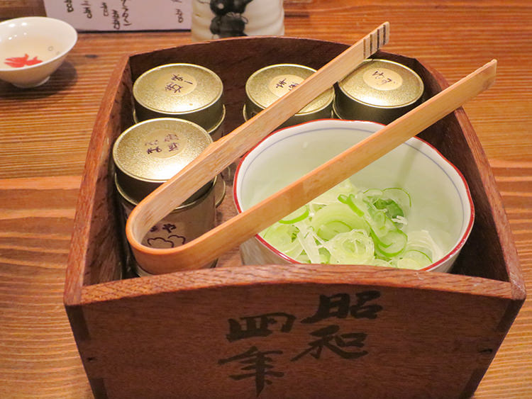 まるのたっぷりの刻み白ネギと女将さん調合の4種の唐辛子(焼一味・まる特製・ゆず・極辛)が入った木箱